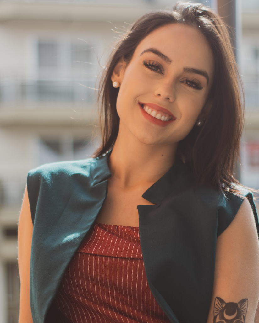 Sofia is smiling and wearing a black vest and red shirt.